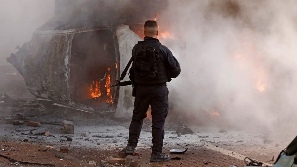 A member of the Israeli security forces next to a burning car